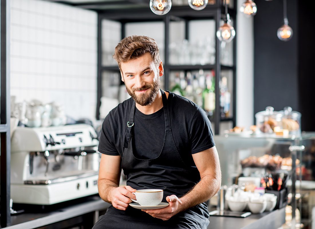 Business Insurance - Friendly Cafe Shop Owner Smiling While Having a Cup of Coffee