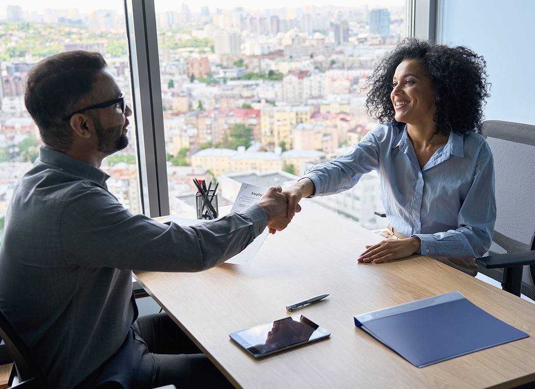 Contact - Friendly Agent at Her Desk Shakes Hands With a Client at Her Office