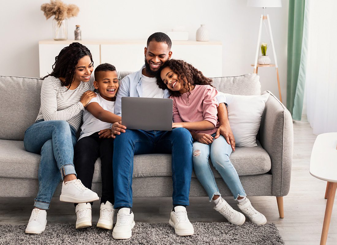 Service Center - Happy Family Smile Together on a Sofa While Using a Laptop at Home