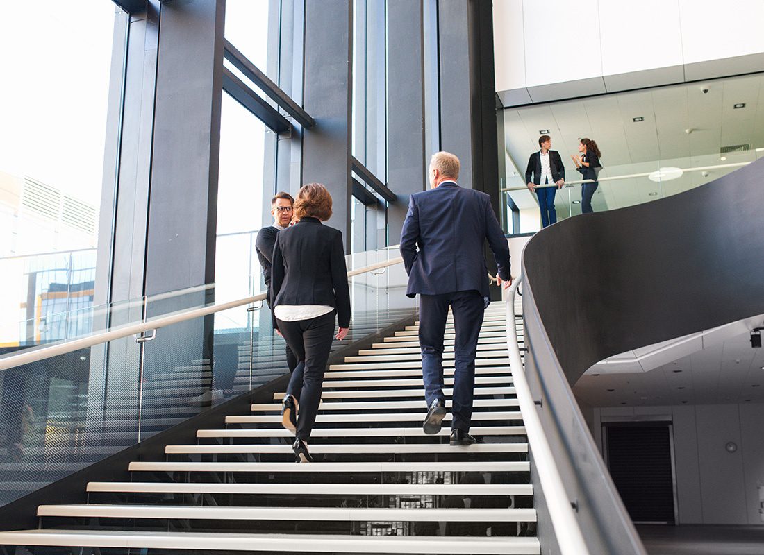 Insurance Solutions - Business Professionals Walking Up Stairs of an Office Lobby